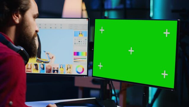 Photo editor using green screen monitor to look at editorial pictures taken with professional camera for fashion magazine in photography studio. Freelancer browsing images on mockup PC in media agency