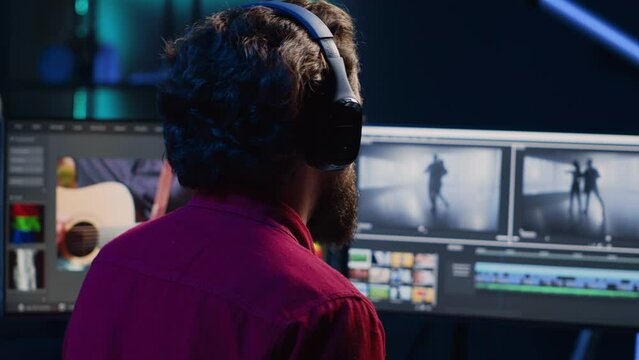 Video editor analyzing film montage before editing color balance and lighting in creative office. Post production studio employee working with raw footage while listening music in headphones