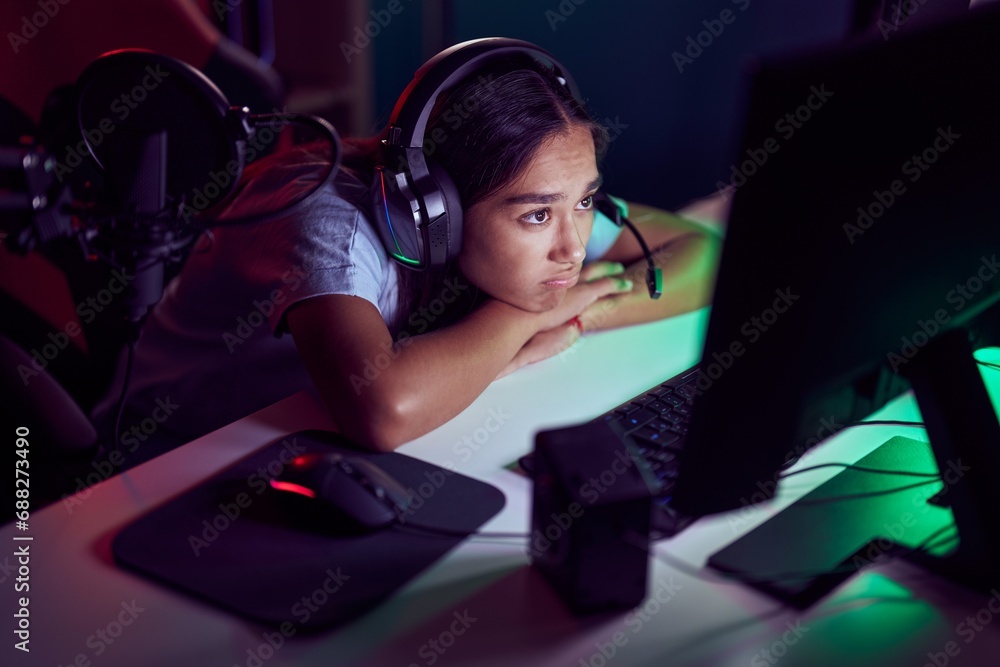 Wall mural Young beautiful hispanic woman streamer stressed using computer at gaming room