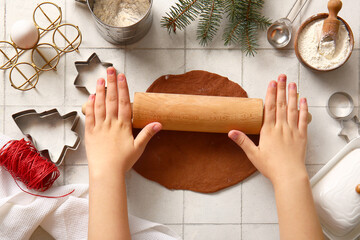 Woman rolling out gingerbread dough for Christmas cookies on white tile background