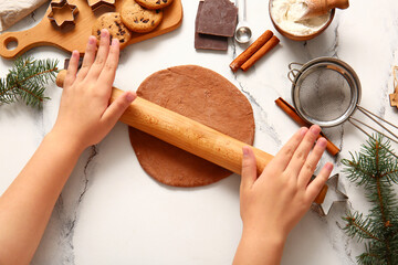 Woman rolling out gingerbread dough for Christmas cookies on grunge white background
