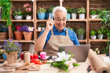 Middle age man with grey hair working at florist shop doing video call smiling with an idea or...