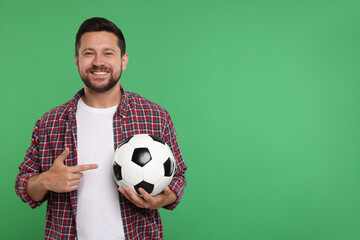 Happy sports fan with ball on green background. Space for text - Powered by Adobe