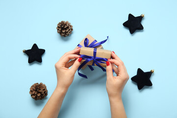 Female hands with red manicure, Christmas gift box and baubles on blue background