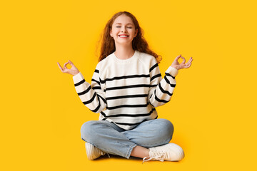 Portrait of relaxed young woman meditating on yellow background