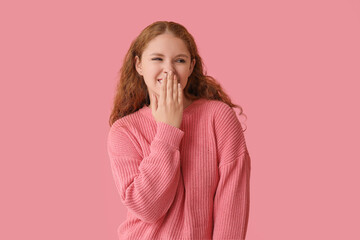 Portrait of ashamed young woman covering her face on pink background