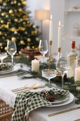 Christmas table setting with festive decor and dishware in room