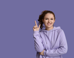 Portrait of ashamed young woman pointing at something on purple background