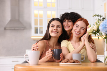 Happy young friends spending time together at table in kitchen