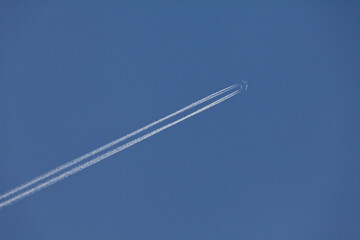 Blue Airplane Cuts Through the Blue Sky, Leaving a Distinctive Contrail. The Canvas of the Sky...