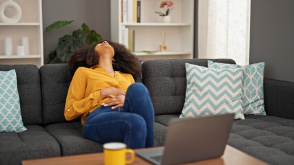 African american woman using laptop suffering for stomach pain at home