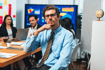 Portrait of businessman or analyst looking at camera with his colleague analyzing data analysis in dynamic business strategy investment planning meeting. Meticulous