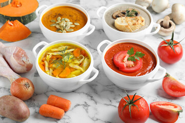 Tasty broth, different cream soups in bowls and ingredients on white marble table, closeup