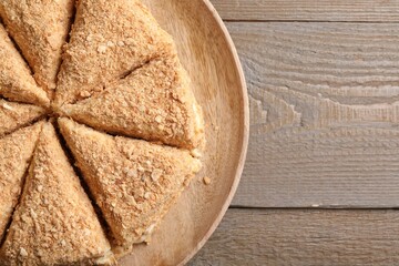 Delicious cut Napoleon cake on wooden table, top view. Space for text