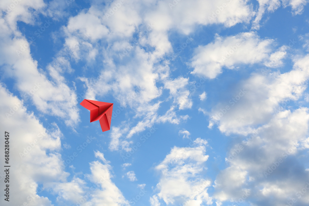 Sticker Red paper plane flying in blue sky with clouds