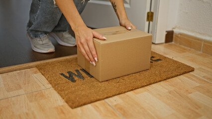 Young woman opening door holding package at home