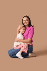 Obraz na płótnie Canvas Beautiful mother hugging with her cute little daughter on brown background