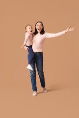 Beautiful mother with her cute little daughter having fun together on brown background