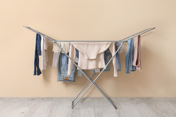 Dryer with winter clothes on floor near beige wall
