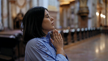 Young beautiful hispanic woman praying at St. Karl BorromÃ¤us church