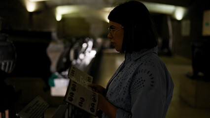 Young beautiful hispanic woman visiting crypt reading brochure at Imperial Crypt in Vienna