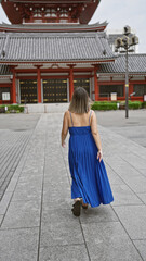 Beautiful hispanic woman in glasses captured walking away, revealing back view at majestic senso-ji shrine, tokyo