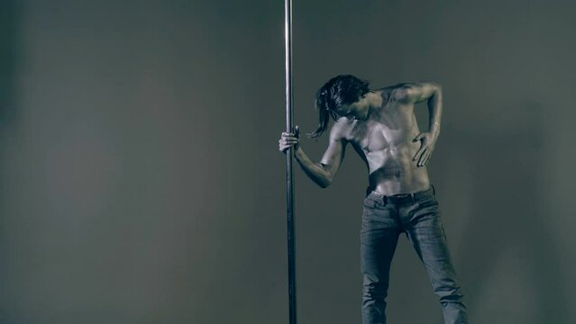 Strip dancer. Sexy man on pole dance. Pole dancer on pylon. Shirtless strong sexy man dancing. Male flexibility, and grace. Guy performing trick on pole. Male athlete doing acrobatic trick.