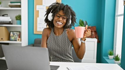 African american woman business worker listening to music drinking coffee at the office