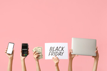 Female hands holding poster with text BLACK FRIDAY, different gadgets, payment terminal and money...