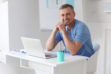 Mature doctor sitting at desk in medical office