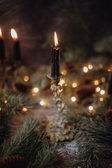 Christmas dark academia vintage winter wooden table with fir branches, pine cones, black candles and twinkle lights covered in fake snow