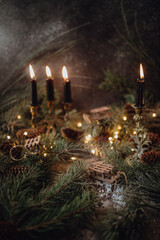 Christmas dark academia vintage winter wooden table with fir branches, pine cones, black candles and twinkle lights covered in fake snow