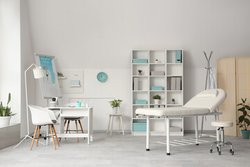 Interior of light medical office with workplace, couch and shelf unit