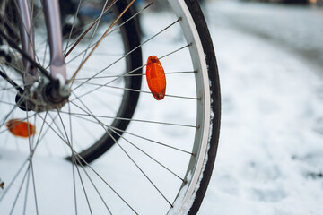 Winter in the city. Bicycle wheels in snow on blurred city background.Snowy winter weather.Bicycle traffic in winter. 