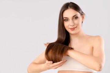 Fototapeta premium Young brunette woman with beautiful hair on light background