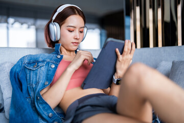 A young woman spends her vacation relaxing by listening to music and surfing the internet.