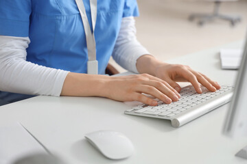 Female doctor working with computer at table in clinic, closeup