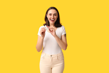 Beautiful young woman with open condom on yellow background. Safe sex concept