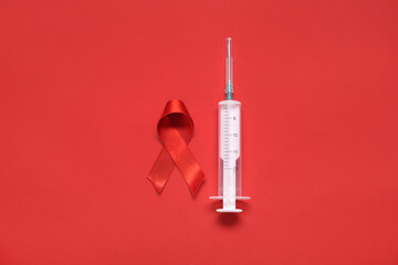 Red ribbon with syringe on color background. AIDS Day concept