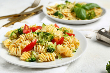 Plate of tasty pasta with broccoli and tomatoes on white background