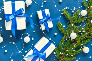 Gift boxes with Christmas tree branches and balls on blue background
