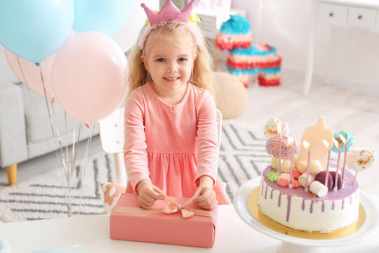 Cute little girl with gift celebrating Birthday at home
