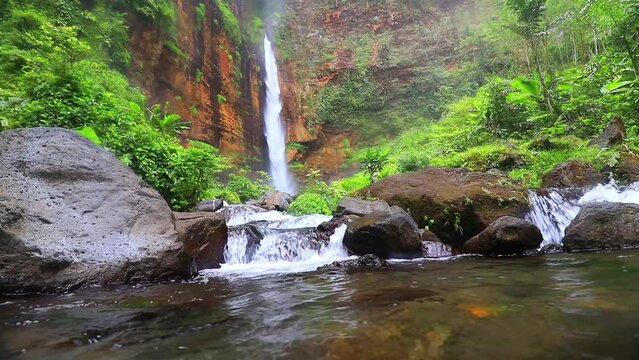 waterfall flowing into a river in a forest, java indonesia