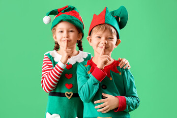 Cute little elves showing silence gesture on green background