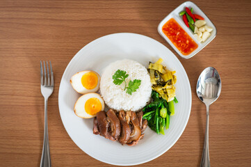 Stewed pork leg with boiled egg and rice on white plate.