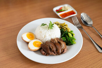Stewed pork leg with boiled egg and rice on white plate.