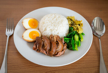 Stewed pork leg with boiled egg and rice on white plate.