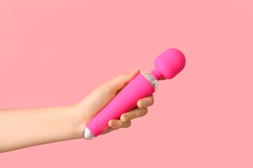 Female hand with vibrator on pink background, closeup
