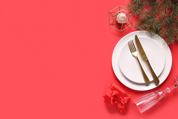 Beautiful table setting with Christmas tree branches, gift box and candle on red background