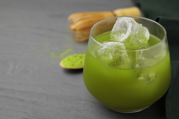 Glass of delicious iced green matcha tea on grey wooden table, closeup. Space for text